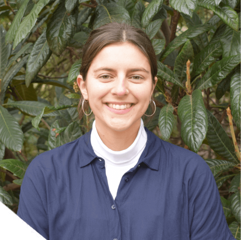 A photo of Becca Stacey - a staff member at Money and Mental Health. Becca is smiling while standing in front of a tree.