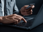 Person holding credit card while typing on laptop - representing online gambling.