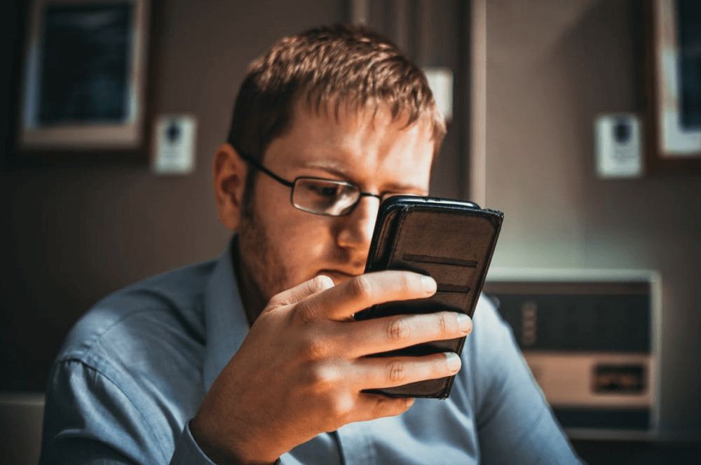 Man looking at his phone for our blog exploring the role of regulation for consumers with mental health problems