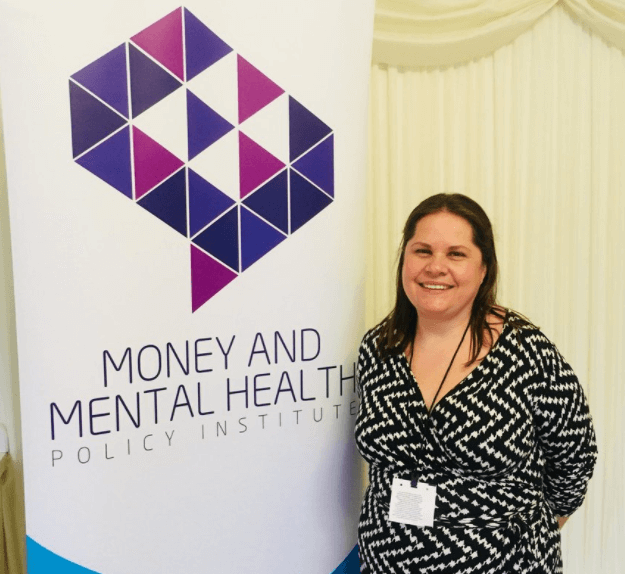 Photo of Nikki Bond by a Money and Mental Health banner for blog about her experience of volunteering with Citizens Advice