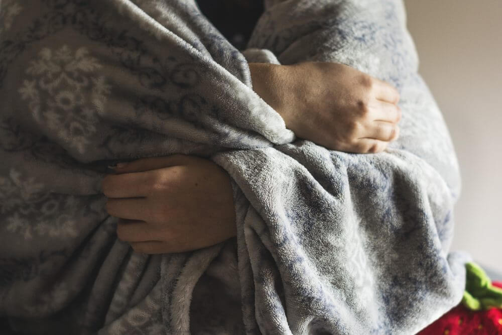 A person wrapped in a blanket for blog about the energy safeguard tariff and mental health