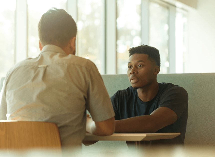 Two men, one sitting across the table from the other.