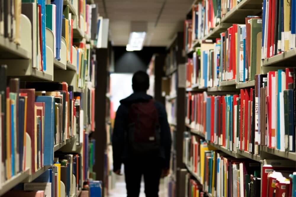 picture of a man standing amongst shelves in a library