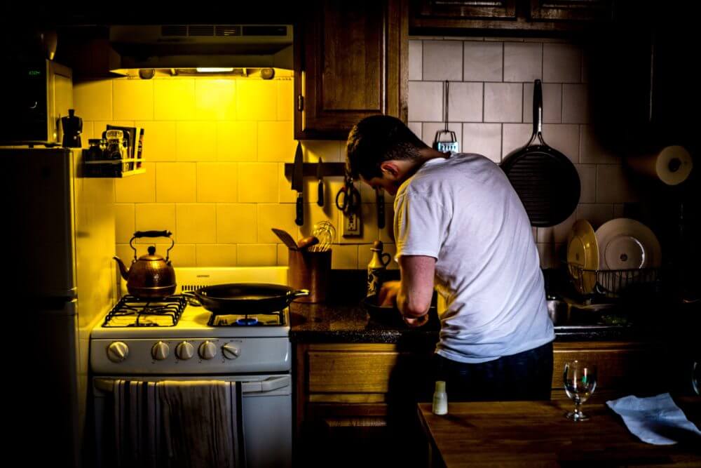 man with frying pan standing beside a lit oven