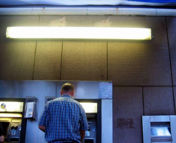 man at cashpoint with his back to camera