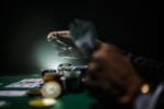 mans hands holding gambling chips at a table playing card game