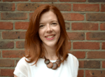 Helen Undy smiling in front of a brick wall.