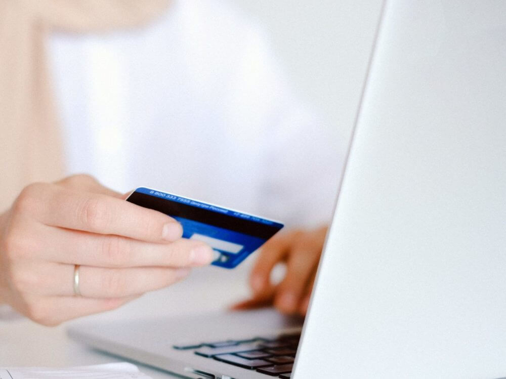 Person holding a bankcard while on a laptop