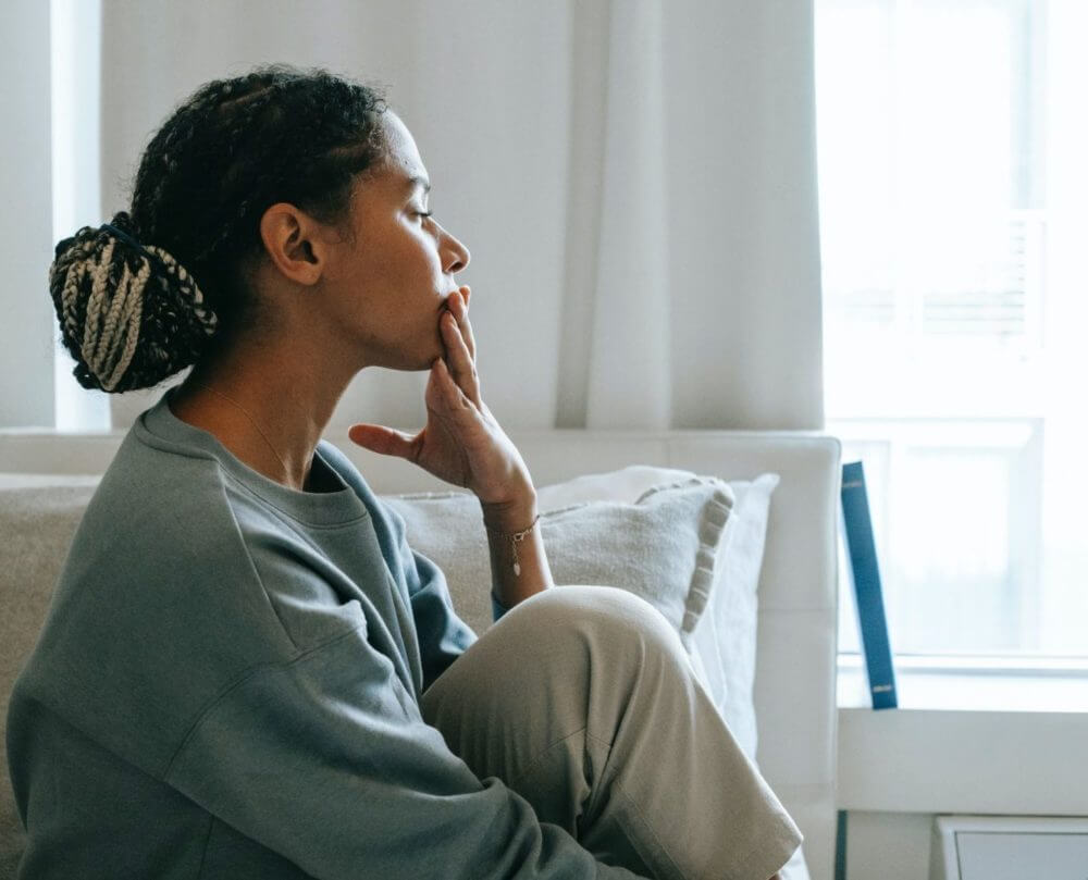 Women in blue jumper sits with legs crossed with hand on chin