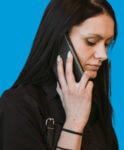 A photo of a woman with long dark hair on a mobile phone call.