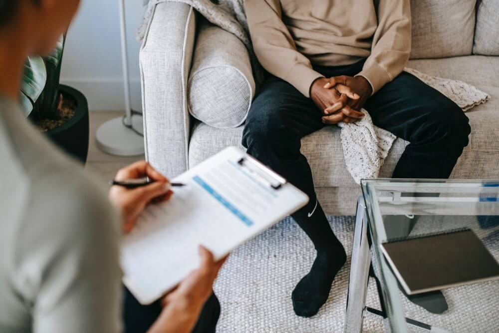 One person holding a clipboard while another sits facing them.