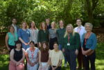 Photo of Money and Mental Health team standing and sitting in front of trees