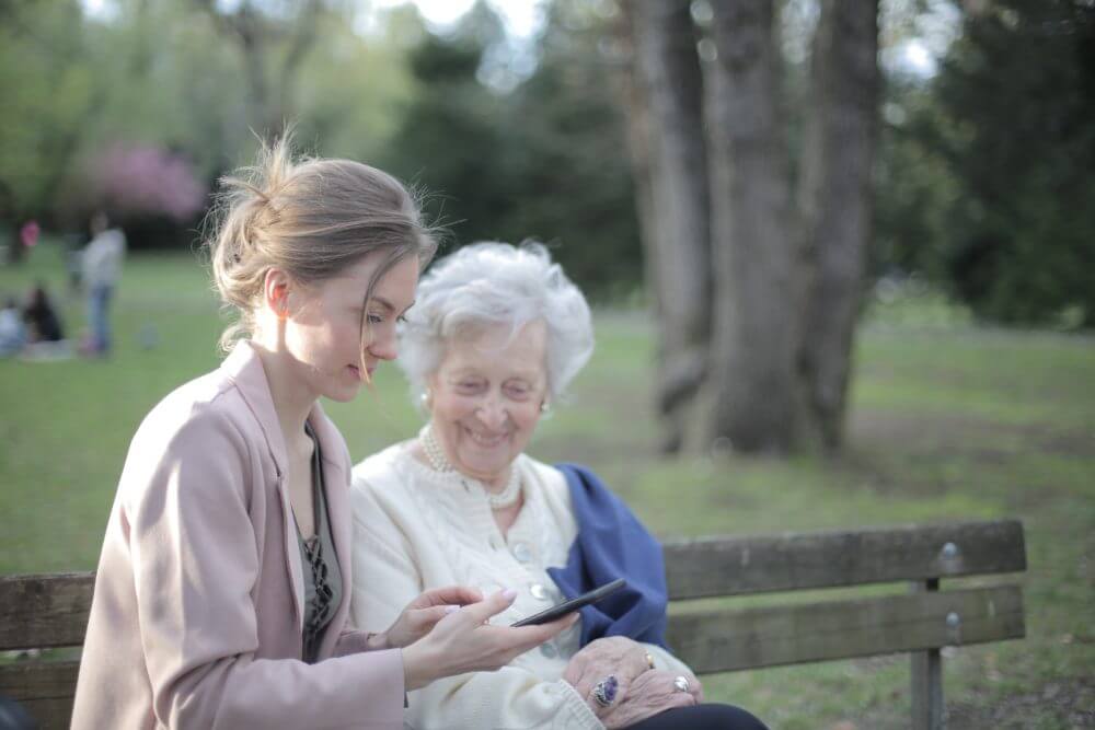 An older woman and a younger woman sat next to each other on a bench.