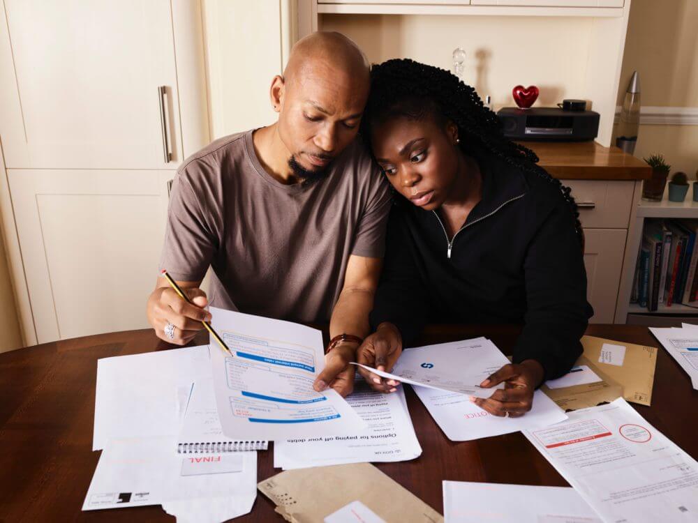 A couple sit at their kitchen table going through their bills