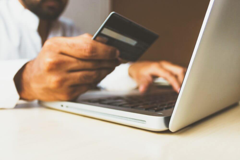 man looking at bank card while on laptop