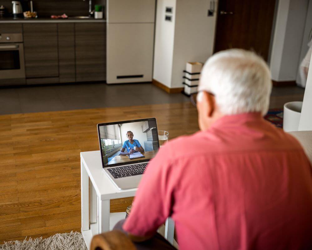 An image of a person in a red shirt speaking on a video call to a health professional.