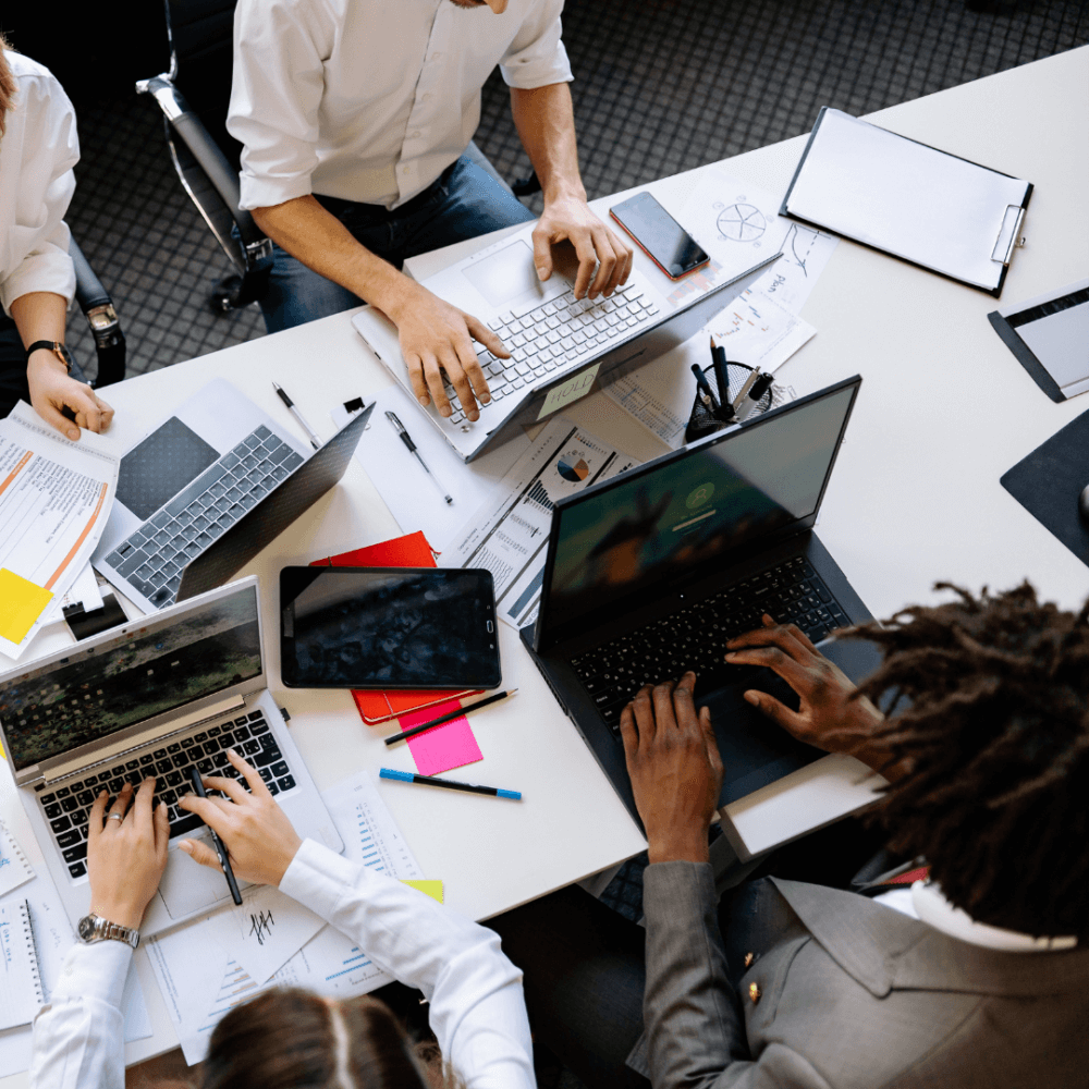 A photo of some people working at a desk on laptops.