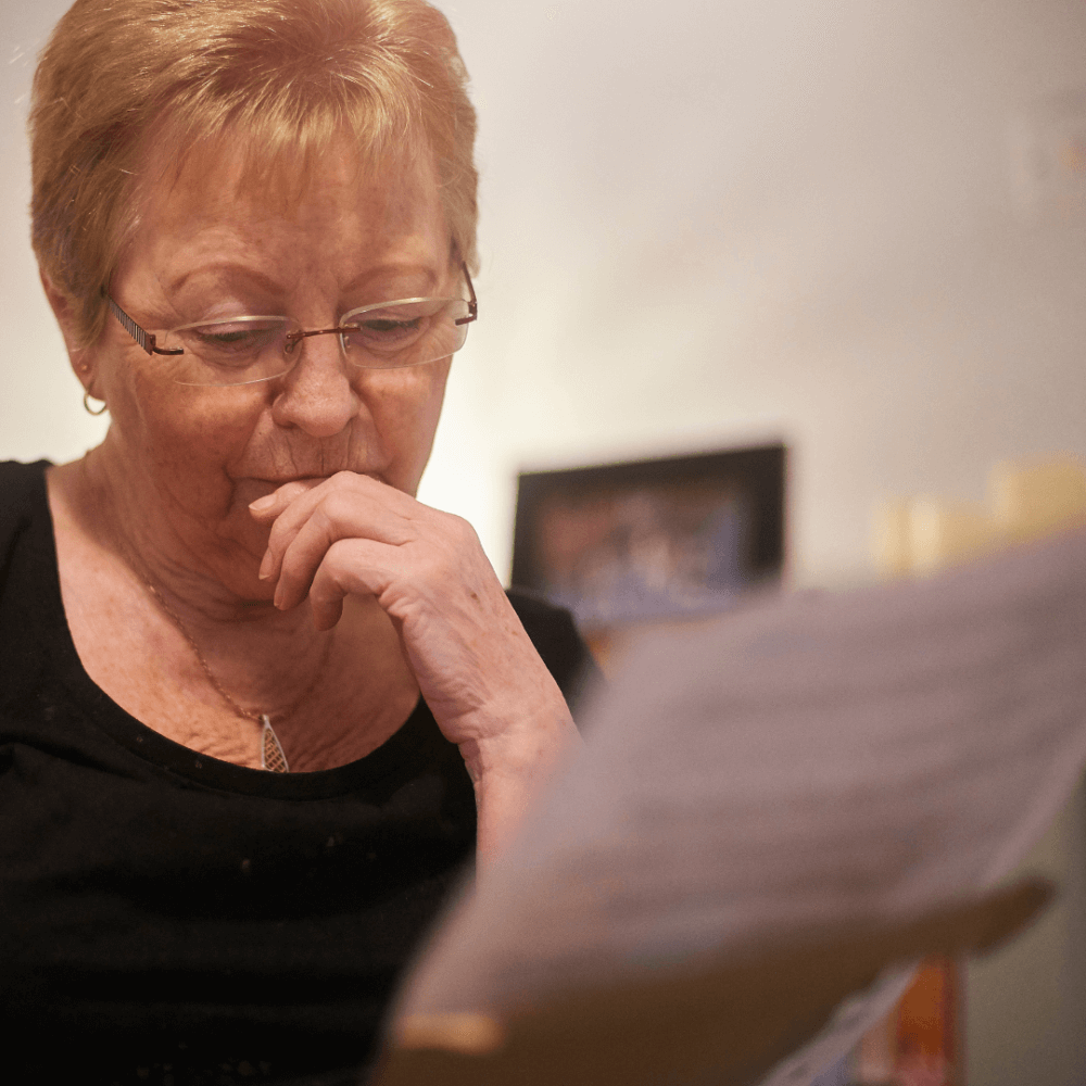 A person at home looking worried at a letter.