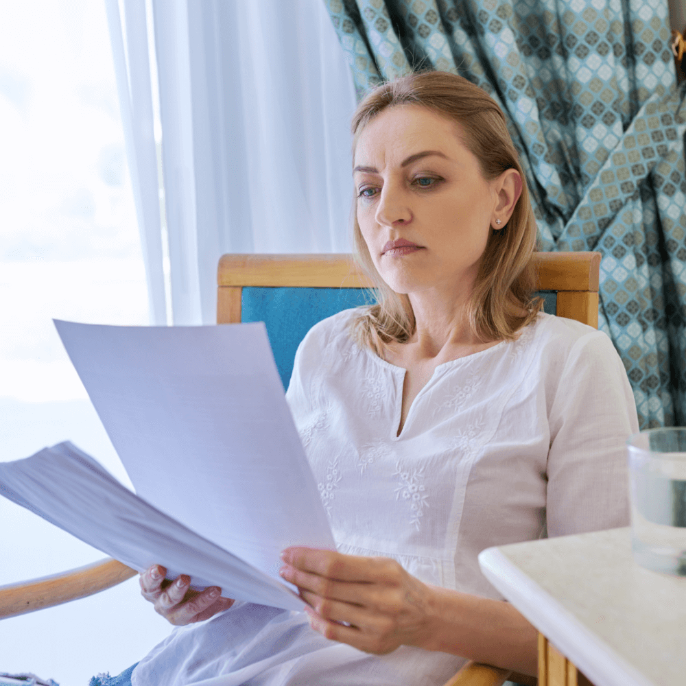 A person reading letters, sitting in what looks like a chair next to a hospital bed.