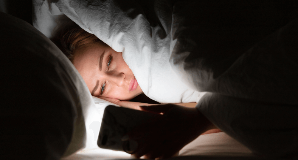 A person in bed looking at their smartphone.
