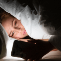 A person in bed looking at their smartphone.