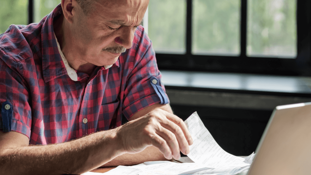A person reading through paper at their desk at home.