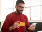 A man smiles at his phone as he does some online banking
