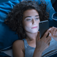 A woman in bed, looking at her phone