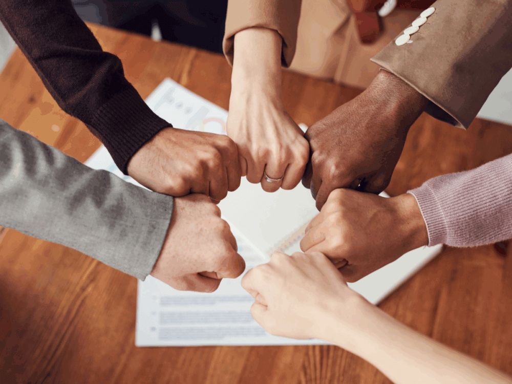 A group of colleagues put their hands together