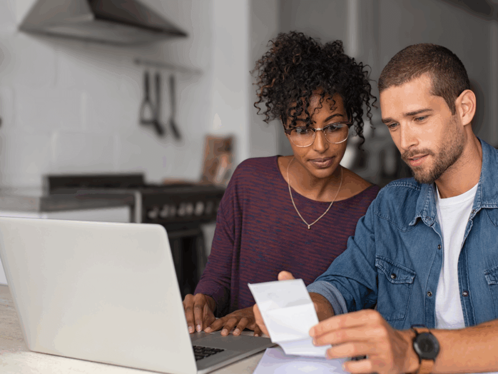 Two people sat at home working on finances - looking at receipts together.