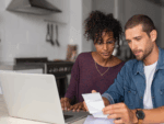 Two people sat at home working on finances - looking at receipts together.
