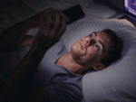 A man looking at his smartphone in bed.