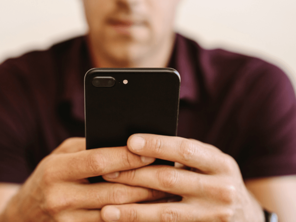 A man holding a mobile phone, signifying gambling harm.