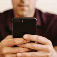 A man holding a mobile phone, signifying gambling harm.