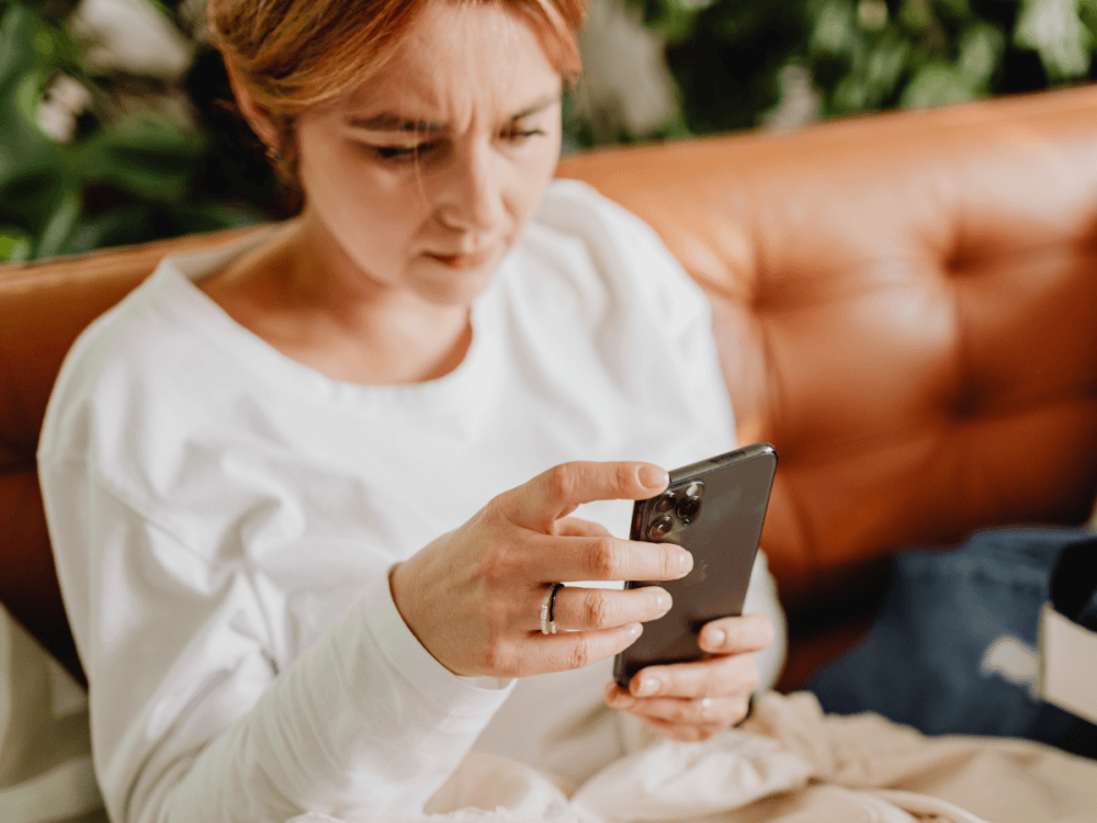 A person at home, holding a mobile phone.