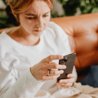 A person at home, holding a mobile phone.