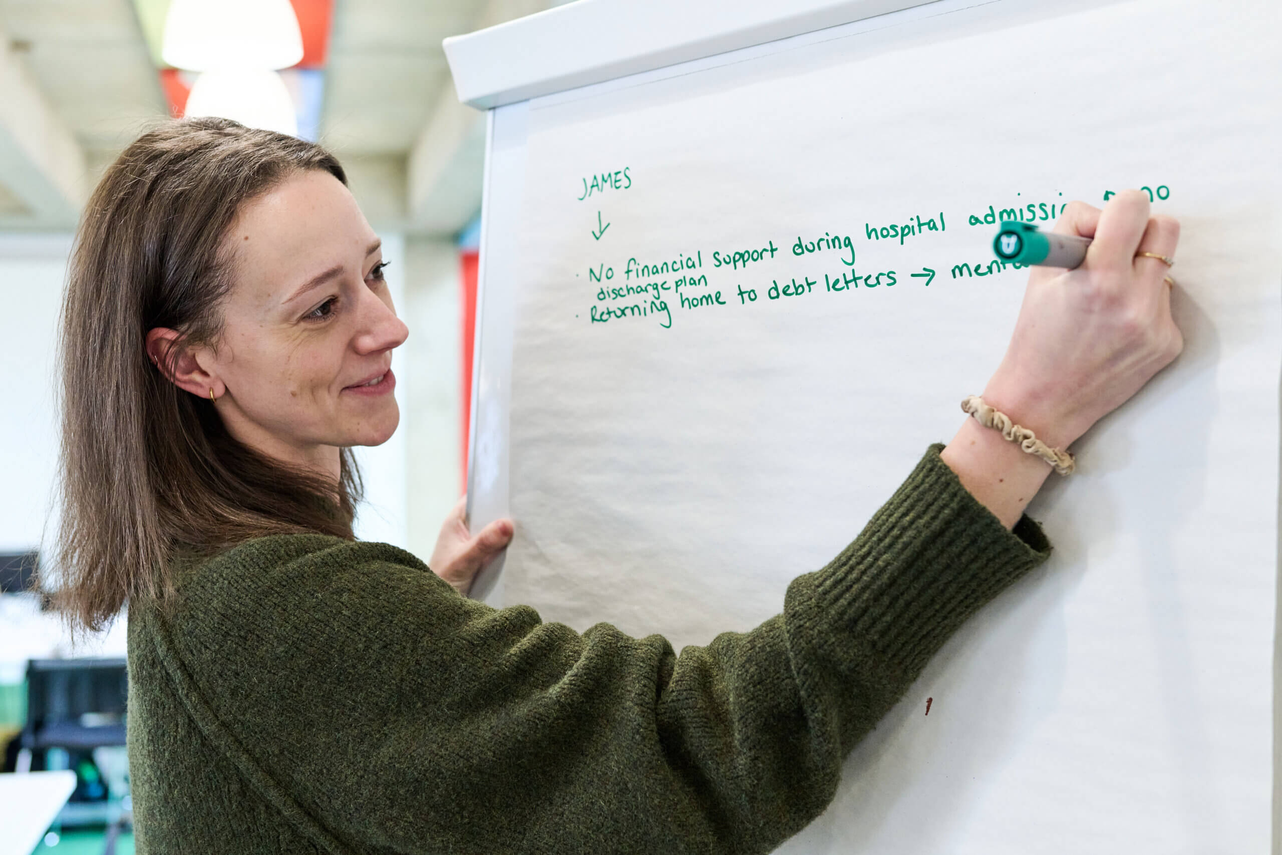 A person making notes flipchart paper - from our event focused on improving support services alongside members of our Research Community.