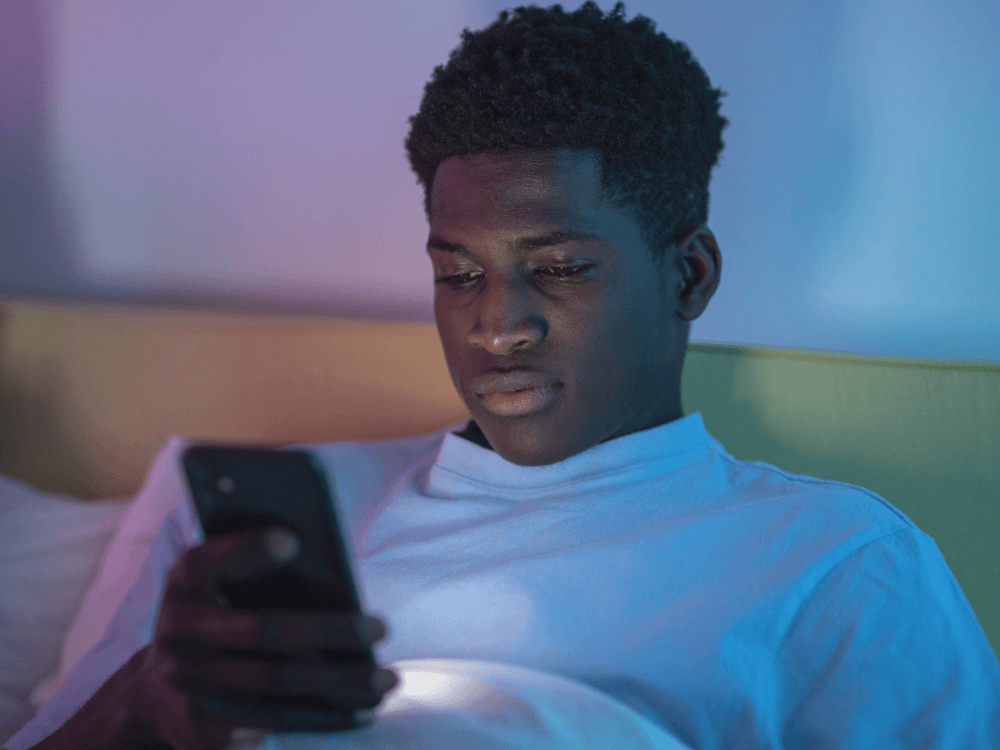 A young man on his phone in the evening.