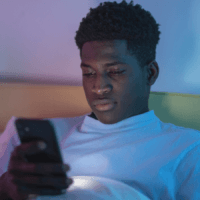 A young man on his phone in the evening.