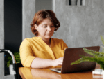 A woman sitting and working at a laptop at home.