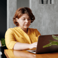 A woman sitting and working at a laptop at home.